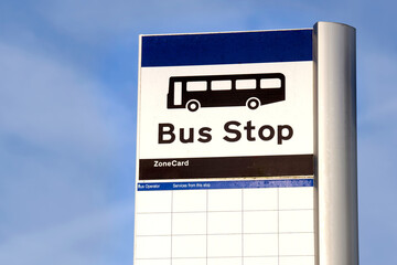 Bus stop sign on post against blue sky