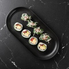 vegan sushi with tofu and vegetables on a black plate. Vegan food concept