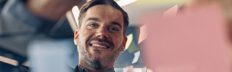 Close up of businessman is glues sticky notes on motivation board in modern office