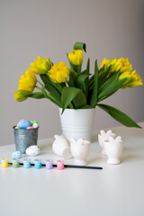 Vase with beautiful flowers, Easter bunny holder with eggs,paints and brush.Vertical banner