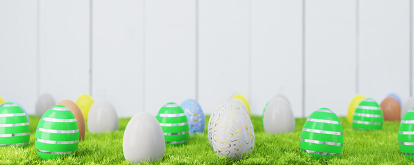 Easter eggs in the grass near a wooden fence. 