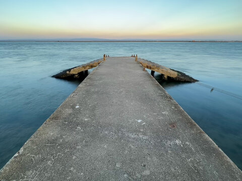 mpty concrete pier with dramatic sky and calm water