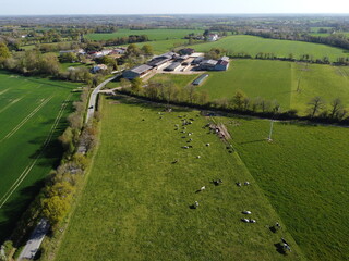 Vue aérienne d'une ferme, des vaches au pâturage et d'un village