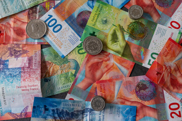 Many coins lie on the scattered banknotes. The Swiss franc is very strong and the Swiss economy is...