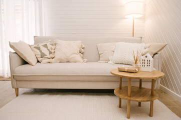 Light interior of the living room of a beautiful house, white sofa, floor lamp and coffee table