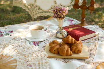 picnic in nature in summer with croissants, book and flowers