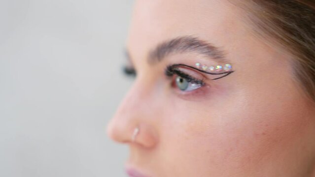 Close up o a woman attaching crystal make up