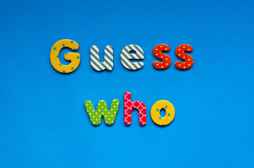 text guess who from bright colored paper letters on blue paper background