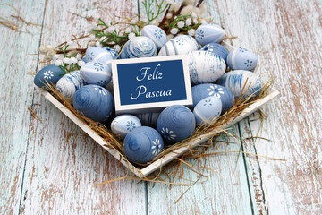 Nido con huevos de Pascua azules y blancos y el texto Feliz Pascua.