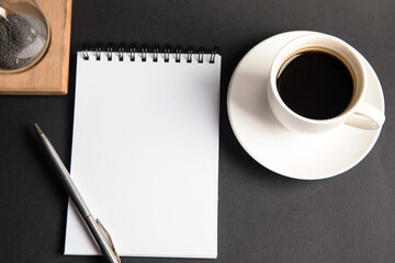 Hourglass, coffee and notepad on table