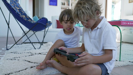 Younger brother looking older sibling play video game on screen console sitting at home living room © Marco