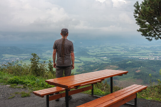 Wooden table and benches, hiker with dreadlocks  and view from Velky Javornik to Frenstat nad Radhostem, Beskid Mountains