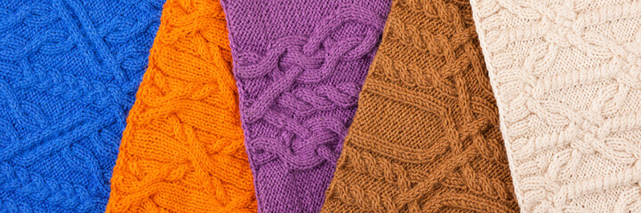 Knitted blue, lilac, brown, orange and beige background. Large knitted fabric with a pattern. Close-up of a knitted blanket. Banner