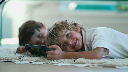 Portrait of joyful child holding tablet device lying on floor turning head to camera smiling. Kids close up face posing