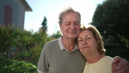 Portrait of a married senior couple standing outside. Older husband with arm around wife. Two elder people close up faces together. Love concept