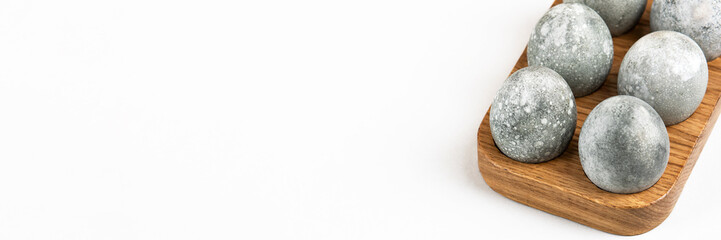 Grey Easter eggs in a wooden stand on a gray background. Minimal Easter concept. Banner