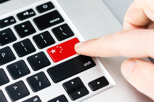 Online International Business concept: Computer key with the China flag on it. Male hand pressing computer key with China flag