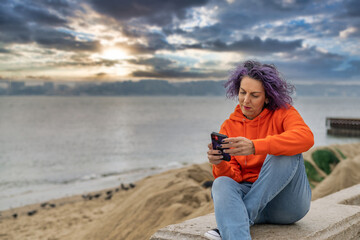 Adult Woman In Casual Clothes Using Her Mobile. She Is Next To The Tajo River In Lisbon, Portugal.