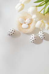 Flat lay easter composition with white tulips in a vase and easter eggs on a light background