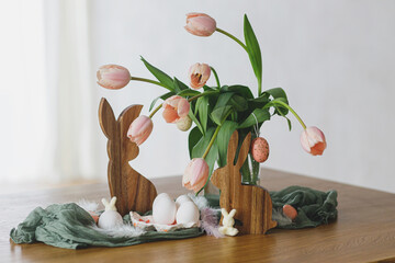 Happy Easter! Beautiful tulips, eggs and bunny decoration on wooden table. Modern farmhouse easter...