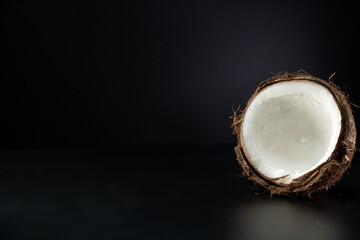 Cracked coconut on a black background. Copy space