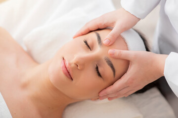 Obraz na płótnie Canvas Beautiful young indian woman receiving acupressure head massage in spa salon