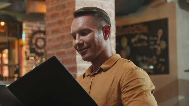 Caucasian man checking menu and choosing dishes while getting ready to make order in restaurant