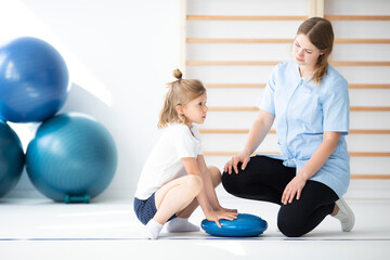 Cute little blond girl exercising with her professional physician