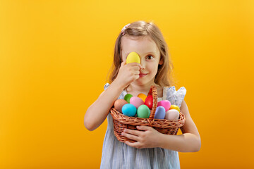 Fototapeta na wymiar A happy smiling girl with a basket full of colored eggs.