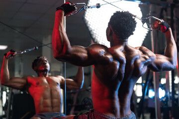 20s Black male working out rear delt and back muscles with cable machine