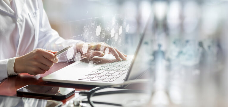 A medical worker works on a laptop on a interface.