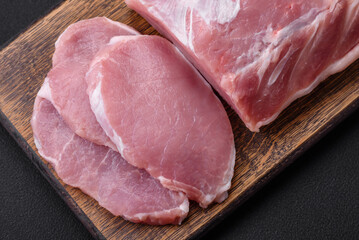 Fresh juicy pork on a wooden cutting board with spices and salt