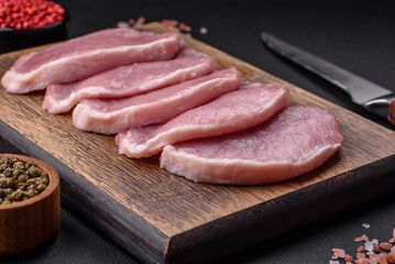 Fresh juicy pork on a wooden cutting board with spices and salt