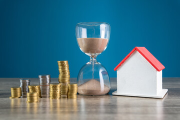 Coins, hourglass and wooden house