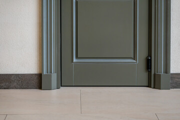 View of a closed door inside an office or cafe. Beige tiles on the floor and granite baseboards...