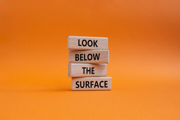 Look below the surface symbol. Concept word Look below the surface on wooden blocks. Beautiful orange background. Business and Look below the surface concept. Copy space