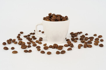 Roasted coffee beans in a white cup on a white background.