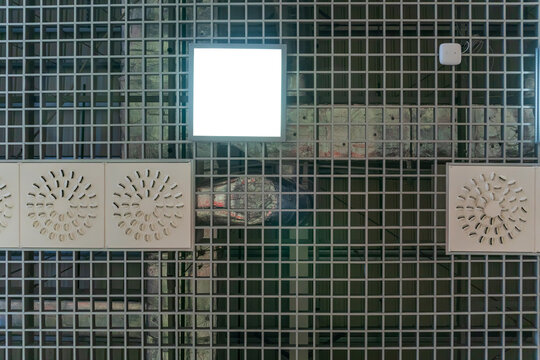 Various lighting fixtures and air conditioning grilles on the ceiling of the restaurant. LED lamps on the suspended mesh ceiling. Industrial air conditioning in the large hall. - Powered by Adobe