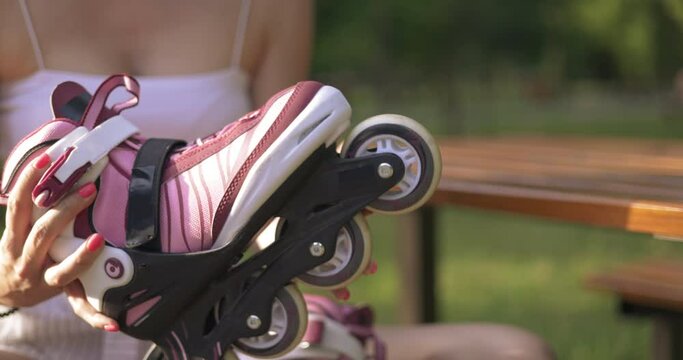 Girl in tight white blouse spins rubber wheels of roller skates