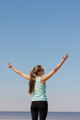 Obraz premium yoga and freedom, sporty woman does warm-up on seashore in morning with hands to sides. fitness millennial female trains, asana breathing practice, healthy lifestyle, love for your body, mental and