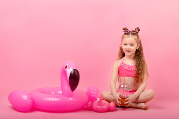 Obraz na płótnie Canvas happy child girl in swimsuit with swimming ring flamingo on a colored pink background