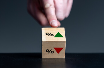 Symbol for the trend of the interest rate. Hand turns wooden cube and changes the orientation of an arrow from down to up. - obrazy, fototapety, plakaty