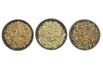 cereal flakes (spelt, oat, rye) in concrete bowls isolated on white background