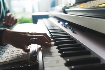 closeup shot of the man playing the electronic piano at home, young musician's lifestyle. High...