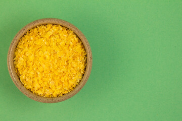Corn grits. In a small container. On a turquoise background. Copy space.