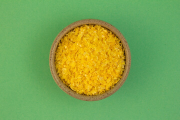 Corn grits. In a small container. On a turquoise background.