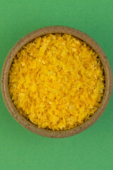 Corn grits. In a small container. On a turquoise background. Vertical.