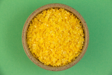 Corn grits. In a small container. On a turquoise background.