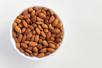 Almond nuts in bowl on white background.