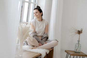 Dunkelhaarige Frau sitzt entspannt am Fenster